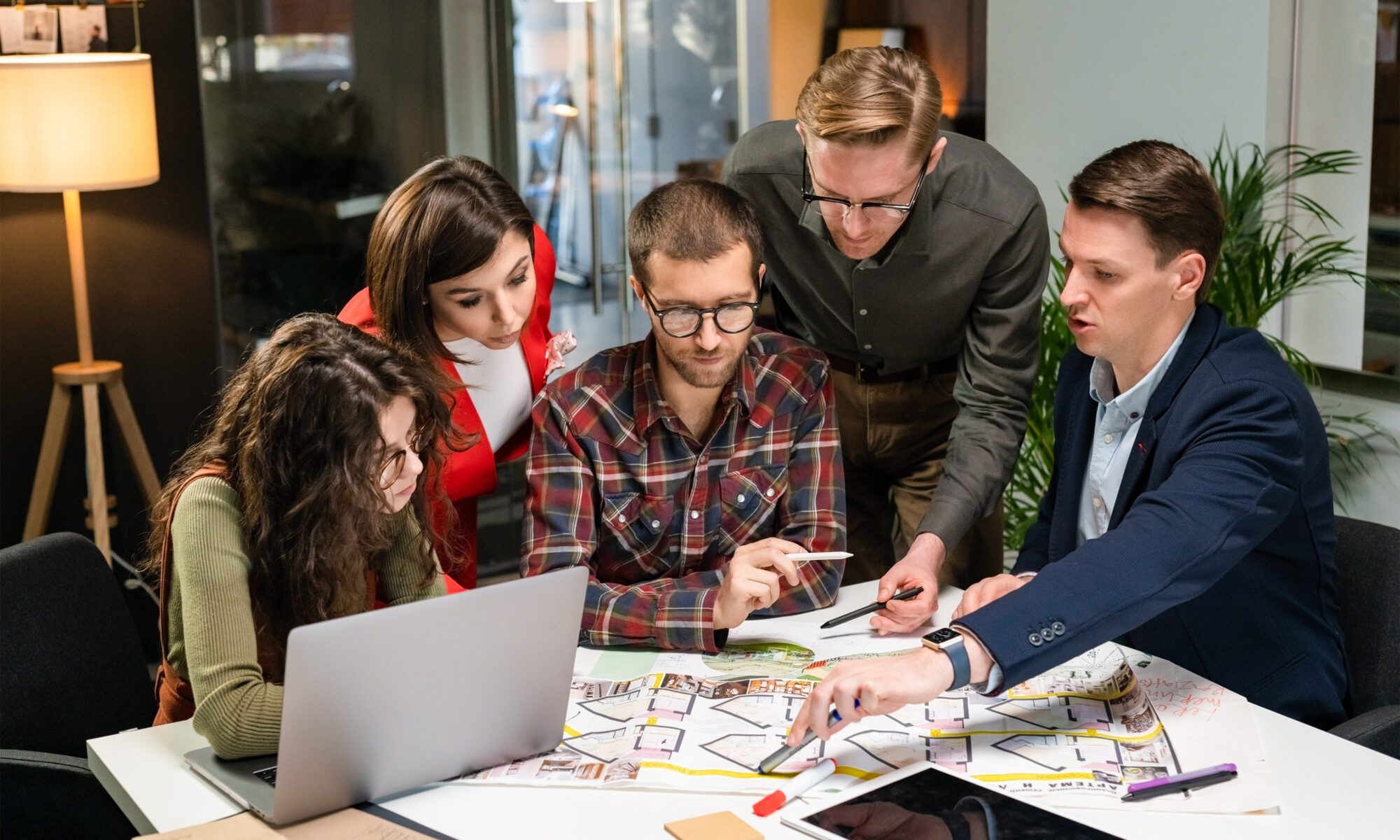 Team of architects working on project paper blueprint. group of modern business people in casual wear discussing architectural designs while sitting in the creative office.